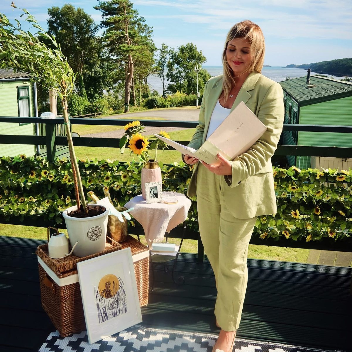 Jan smiling on a seaside deck, holding her ceremony folder