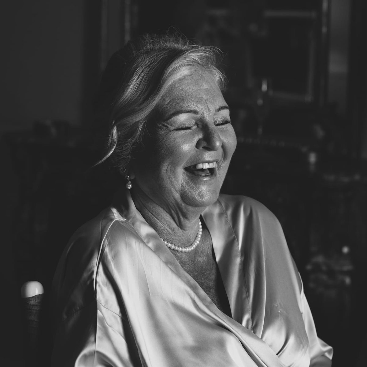 A woman laughing with her head thrown back, in black and white
