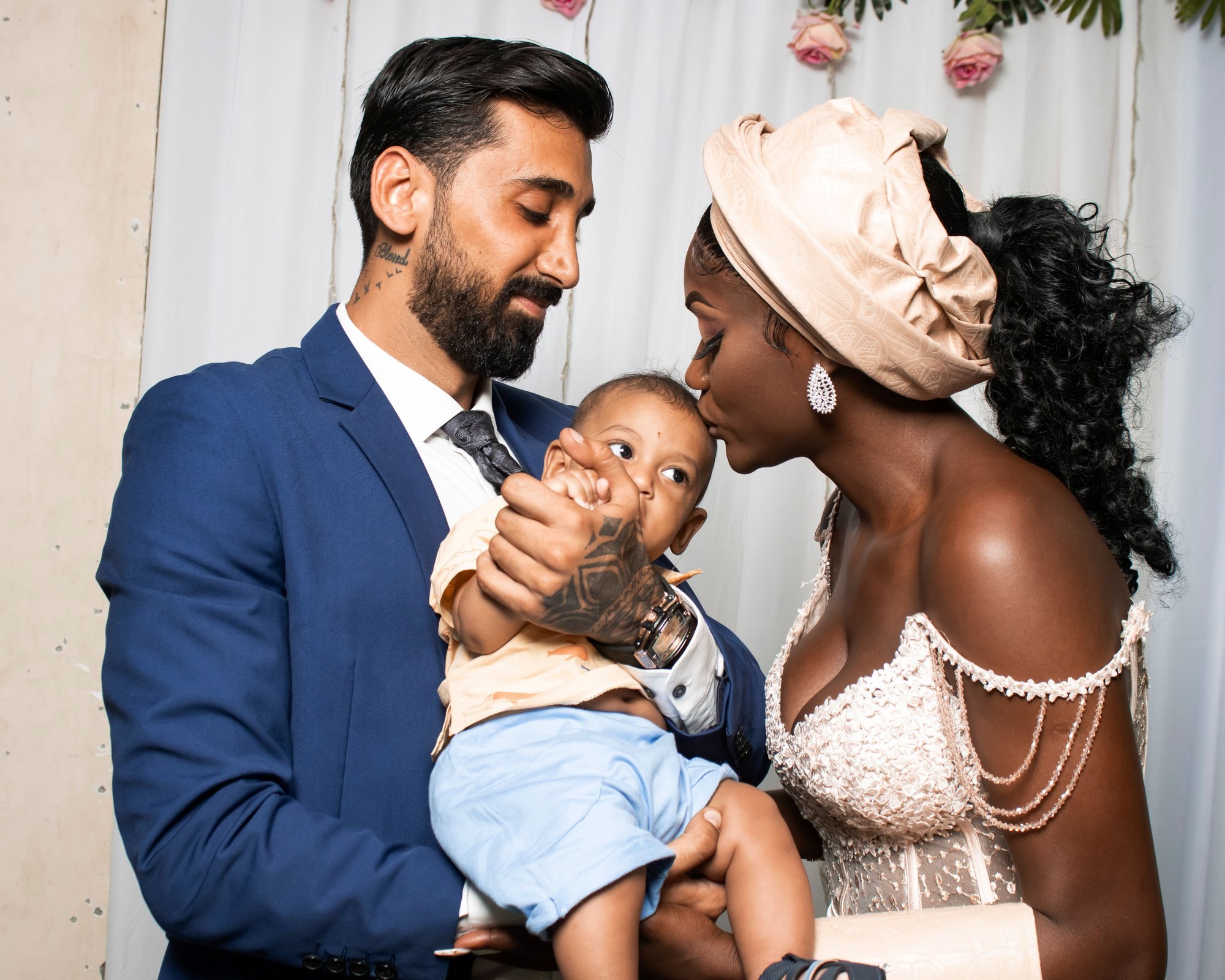 A mother kisses her baby's forehead as the father holds him close